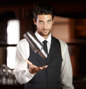 Portrait of a handsome young bartender mixing a cocktail for a customer