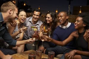 Group Of Friends Enjoying Night Out At Rooftop Bar