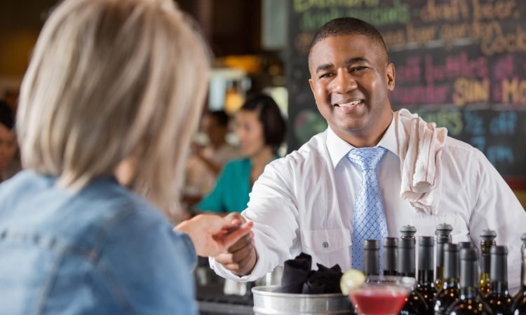 Bartender accepting credit card from customer to pay bar tab